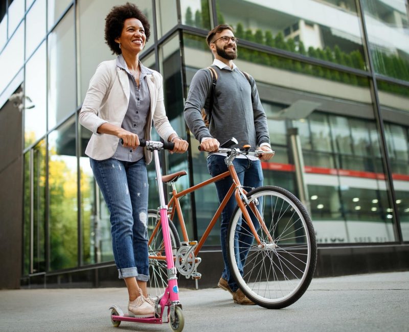 Happy couple using electric scooter, bicycle in city. Green eco energy concept with zero emission